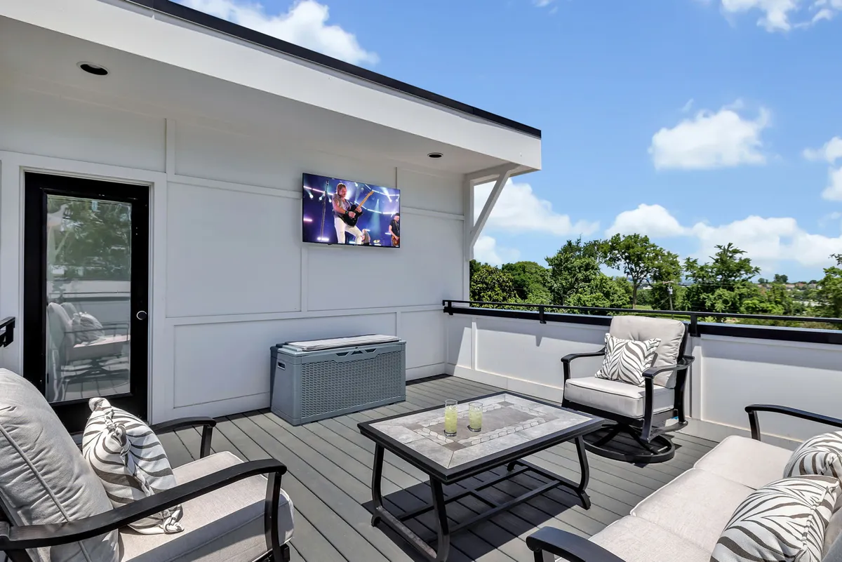 An inviting rooftop or patio space with outdoor seating, a television, coffee table, and scenic landscape views. The area is designed for relaxation and social gatherings under the open sky, with plenty of room for pets and their owners to unwind after a day of exploring.