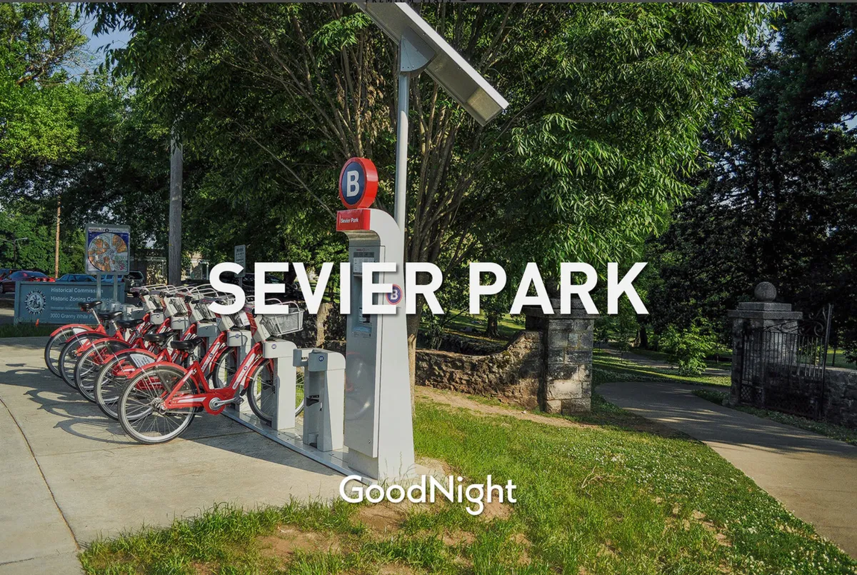 An inviting park scene with a bike-sharing station, clear park signage, and lush greenery. The area is vibrant and suggests opportunities for biking, walking, and community activities, making it ideal for family outings and exploration.