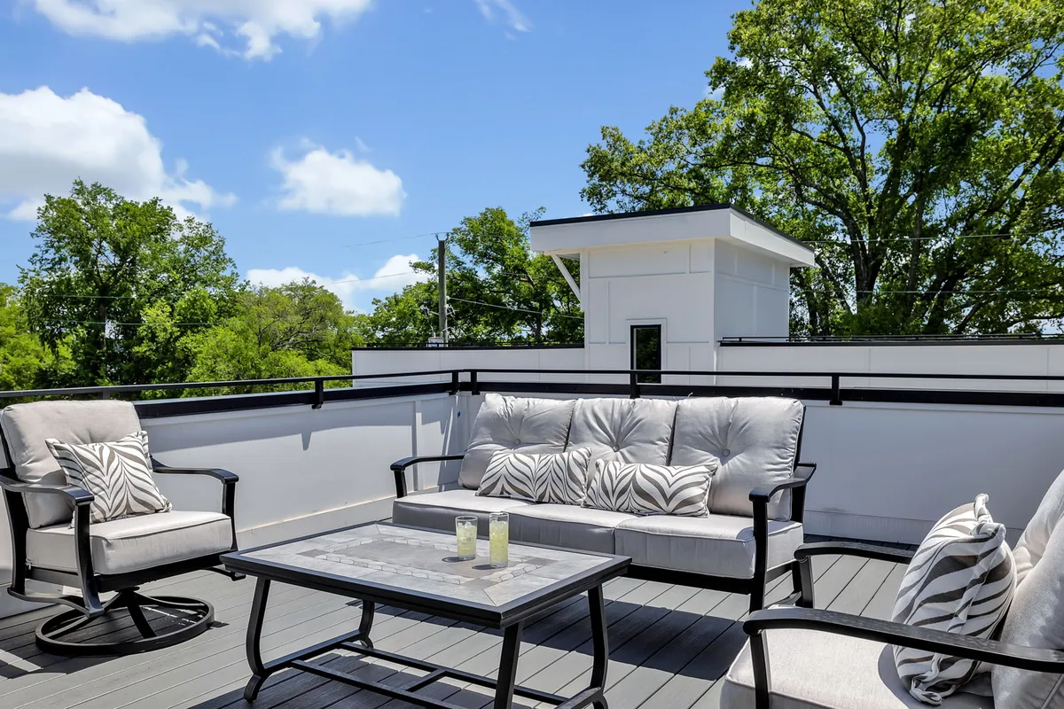 A comfortable and stylish outdoor lounging area with a chic table and surrounding greenery, creating an ambiance perfect for evening relaxation or stargazing. The layout invites guests to unwind and appreciate the cityscape.