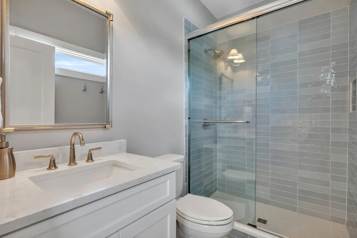 A bright, modern bathroom featuring a vanity with a large mirror and a glass-enclosed shower. The fresh and inviting design makes it ideal for daily routines and quick refreshes after a day of fun.